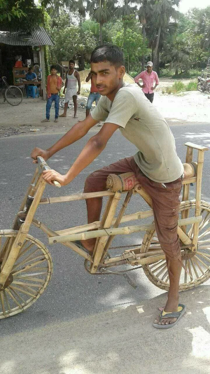देसी बांस की लकड़ी से पूरी तरह तैयार साइकिल पर बैठा हुआ एक भारतीय युवक